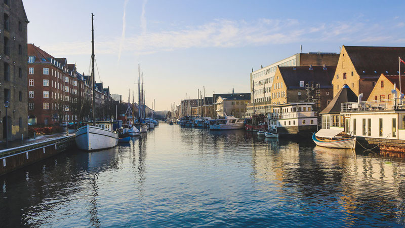 wide shot of boats on the body of water near buildings in christianshavn copenhagen denmark